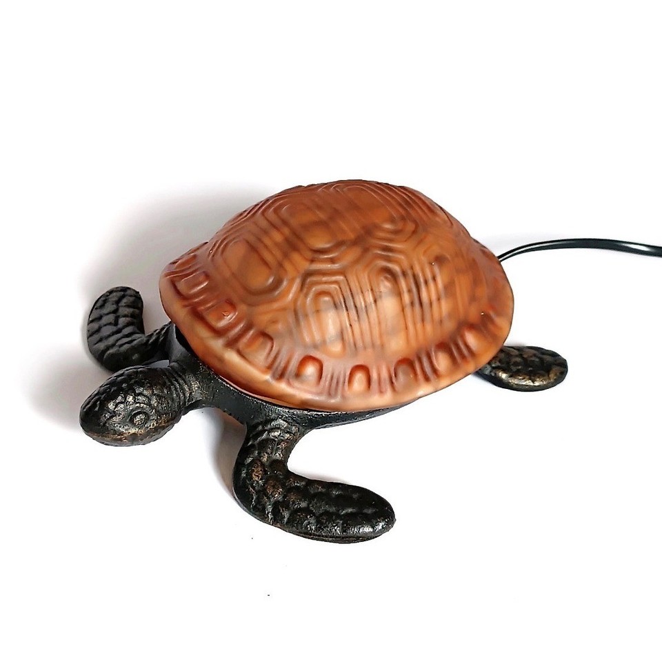 An amber frosted glass turtle lamp on a cast bronze base — moody, sculptural lighting that's also a conversation piece.