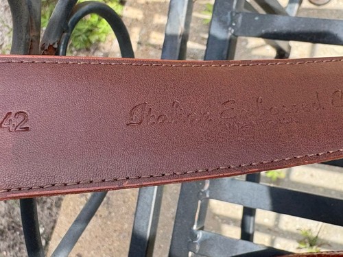 Brown leather belt with embossed calf, “Torino & Co., Made in USA,” on black background.