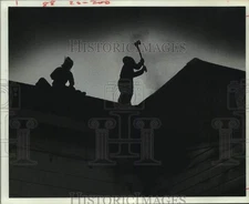 1977 Press Photo Houston fireman swings ax atop roof of Johns & Co. Funeral Home