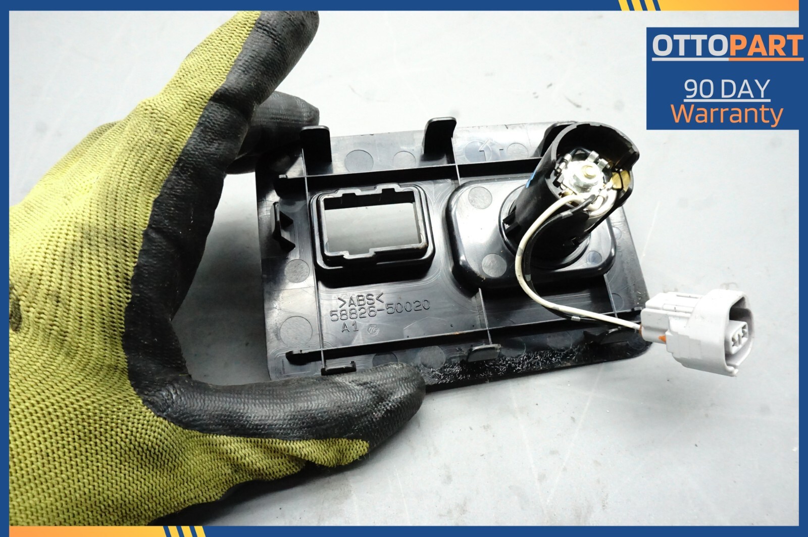 Black 2007-2012 Lexus LS460 LS460L center console auxiliary adapter with blue text label and yellow gloves.