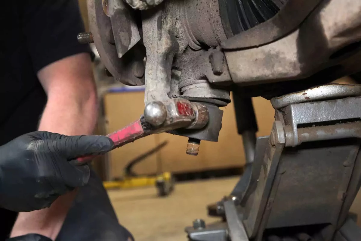 A mechanic smacks the knuckle to separate the pin.