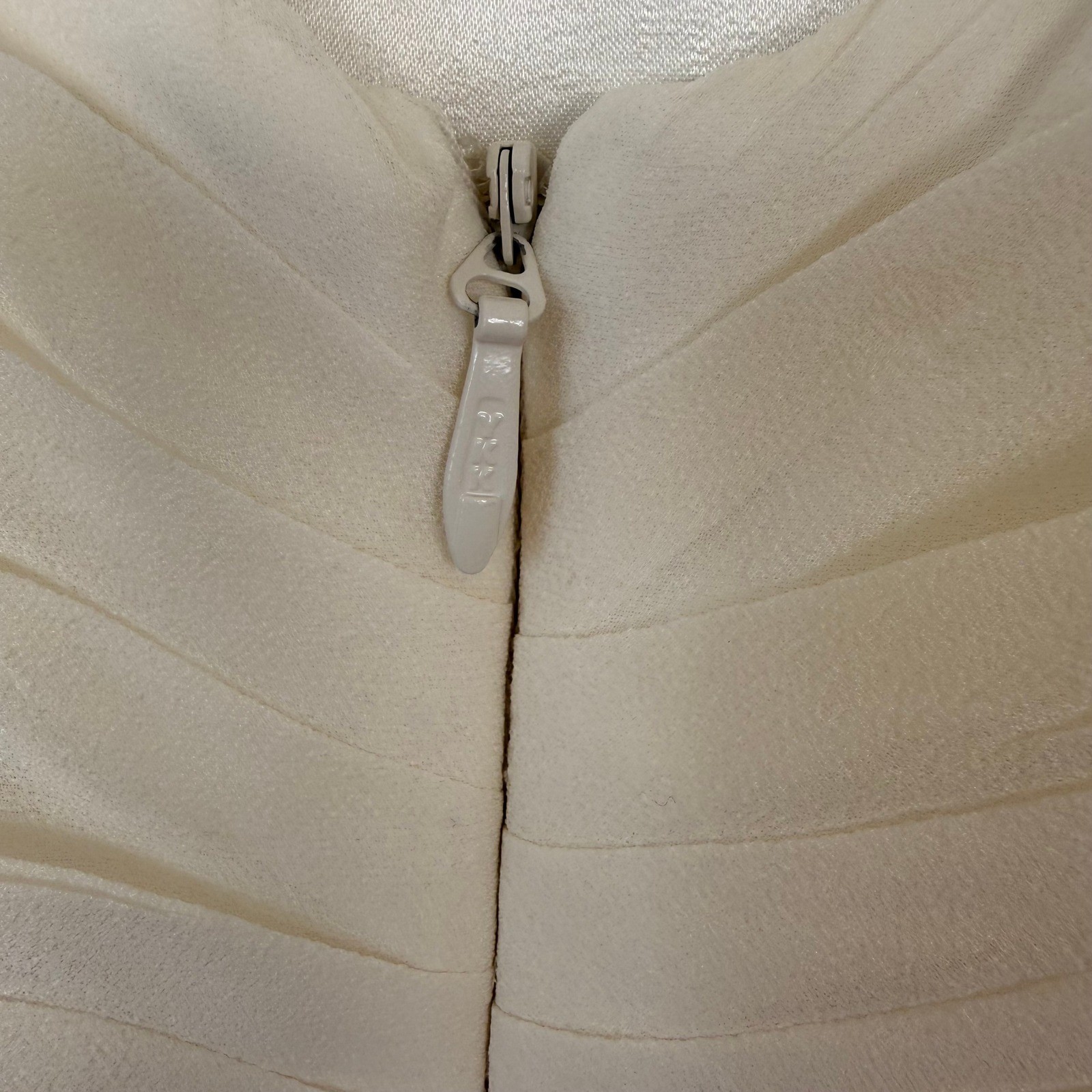 Silver zipper with chain detail on ivory silk wedding dress made in USA, shown on close-up of textured bodice.
