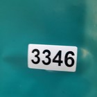 White rectangular Hackett London polo shirt label with black digits 3346, displayed on a teal racing team polo shirt.
