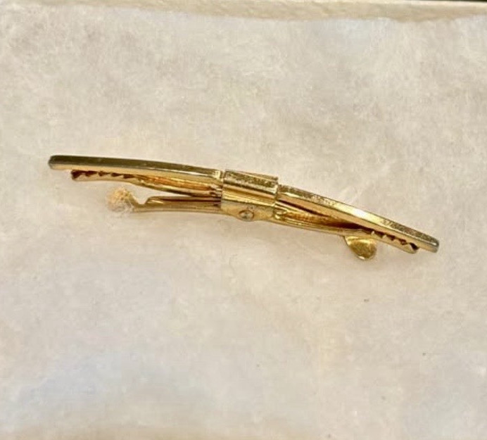 A curved Hickok tie clip — a named mid-century American brand with a collector following, and an elegantly simple piece of wearable history.