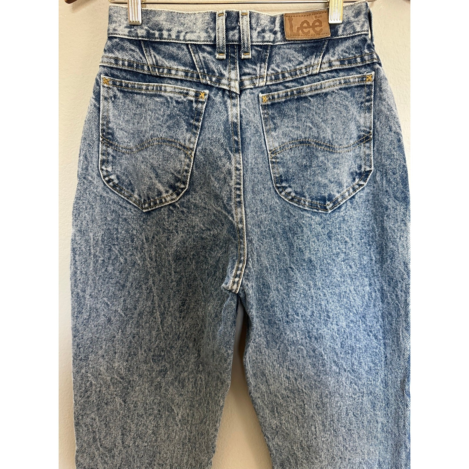 Back view of 90s vintage Lee High Rise Mom Jeans in blue distressed denim with two pockets and brown leather patch on waistband.