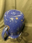 Wartime blue enamel granite pitcher with tan interior, worn white patches, and visible “U.S.N.” markings on side.