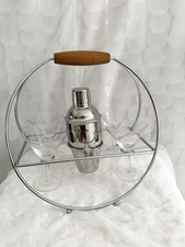A chrome martini shaker with wooden handle and matching glasses in a caddy — a mint-condition set that's ready to gift straight out of the box.