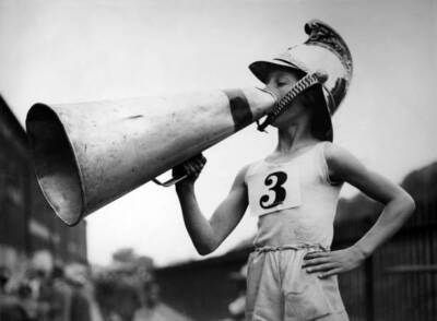 Little boy wearing helmet uses megaphone urge his friend race - 1932 Old Photo