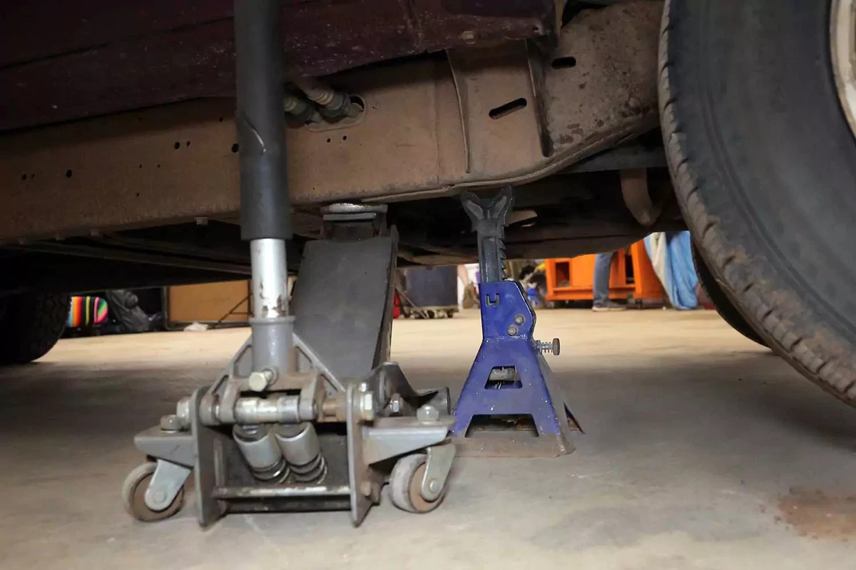 A vehicle lifted with a floor jack and jack stand.