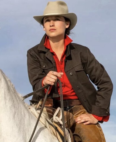 Brown canvas FILSON women’s jacket with red plaid shirt, white hat, and tan leather belt on horseback.