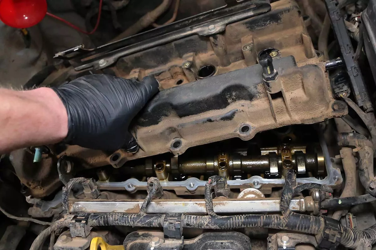 Mechanic reinstalling the valve cover with the new gasket installed.