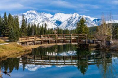 Holzbogen-Fußgängerbrücke im Cascade Ponds Park an einem sonnigen Herbsttag, sch