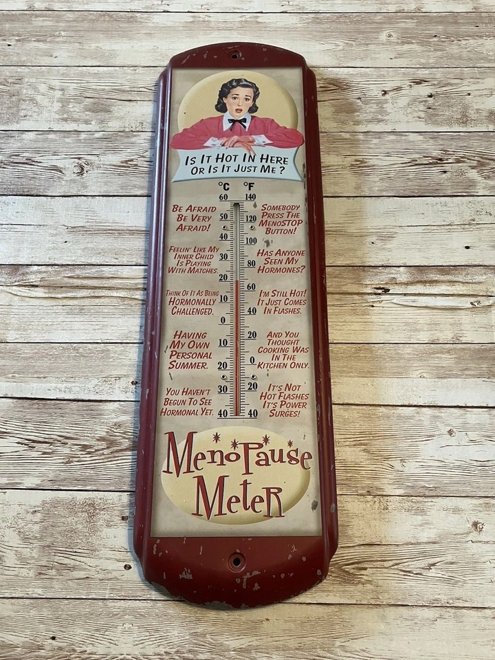 A vintage tin thermometer styled like old-school advertisement signage but labeled 'Menopause Meter' — it's a functional retro wall piece with a sharp, self-aware punchline.