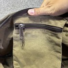 Brown canvas crossbody bag with front zipper pocket, dark brown leather trim, and two snap buttons on strap.