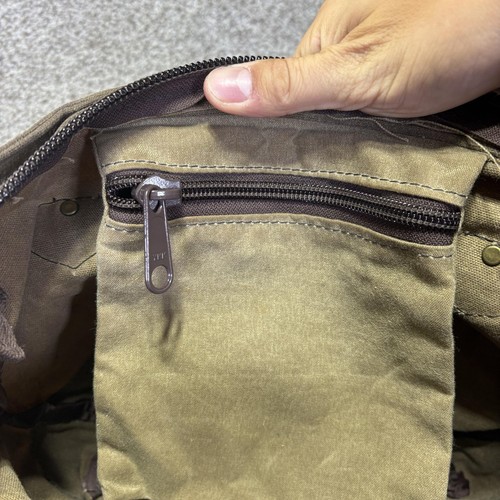 Brown canvas crossbody bag with front zipper pocket, dark brown leather trim, and two snap buttons on strap.