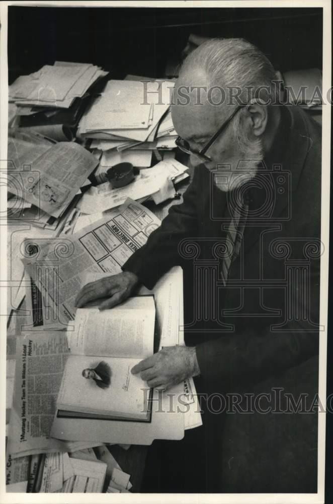 Press Photo Man Studying Book and Papers at Desk - sya07668
