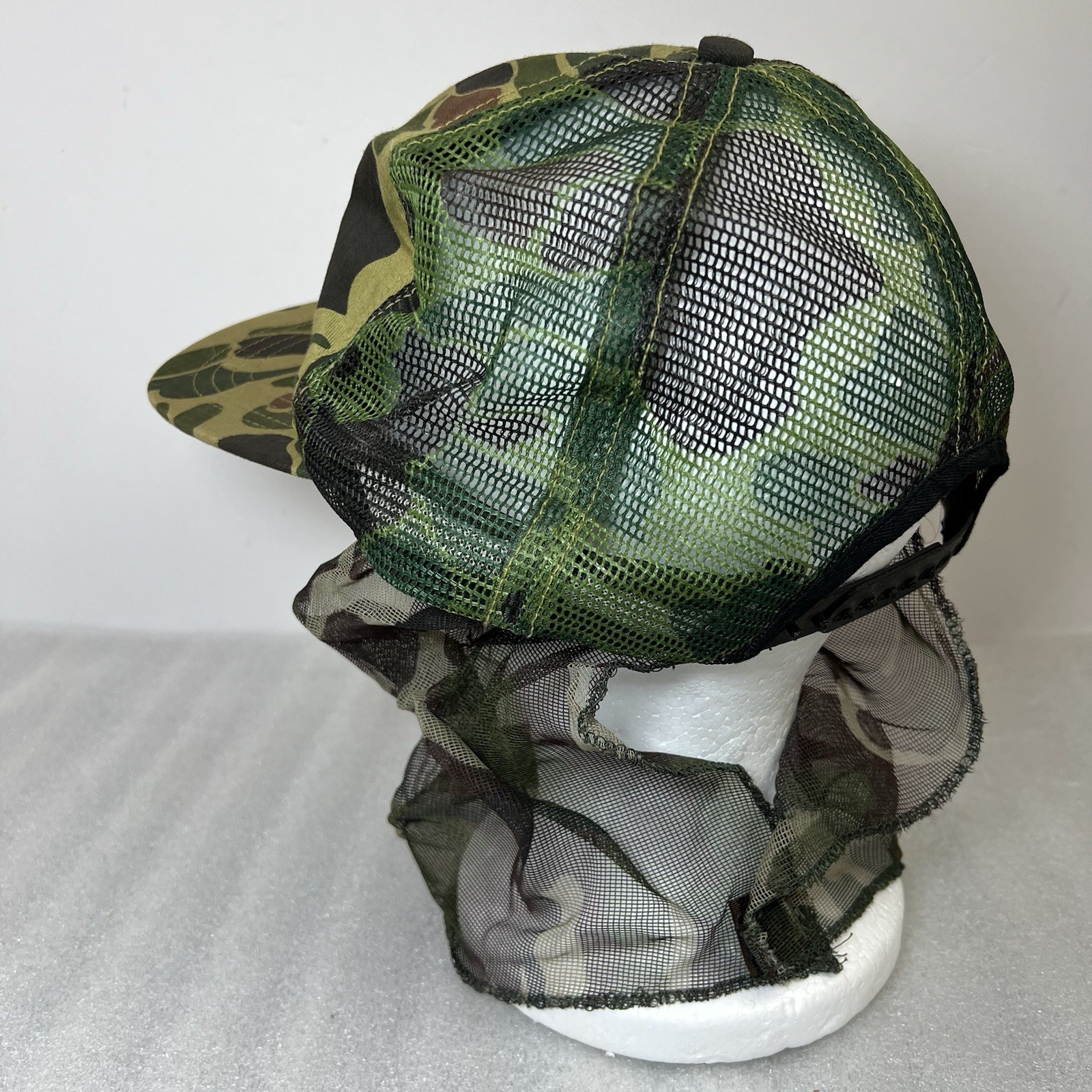 Green and brown camouflage Vtg hat with mesh front and dark green mosquito netting on the sides.