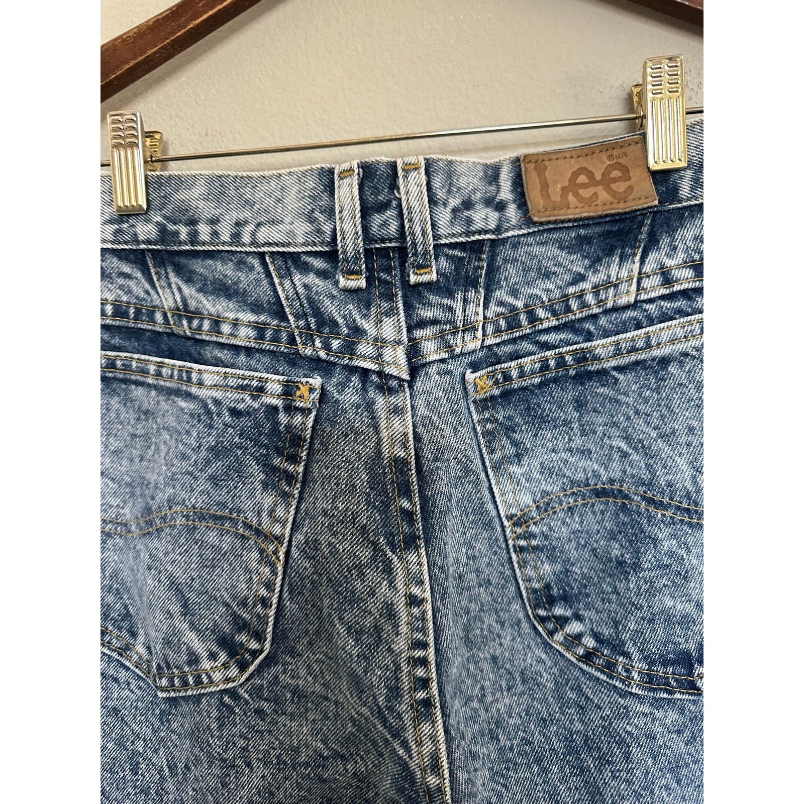 Light blue high-rise vintage Lee jeans size 8 with back pockets, made in USA, on wooden hanger.