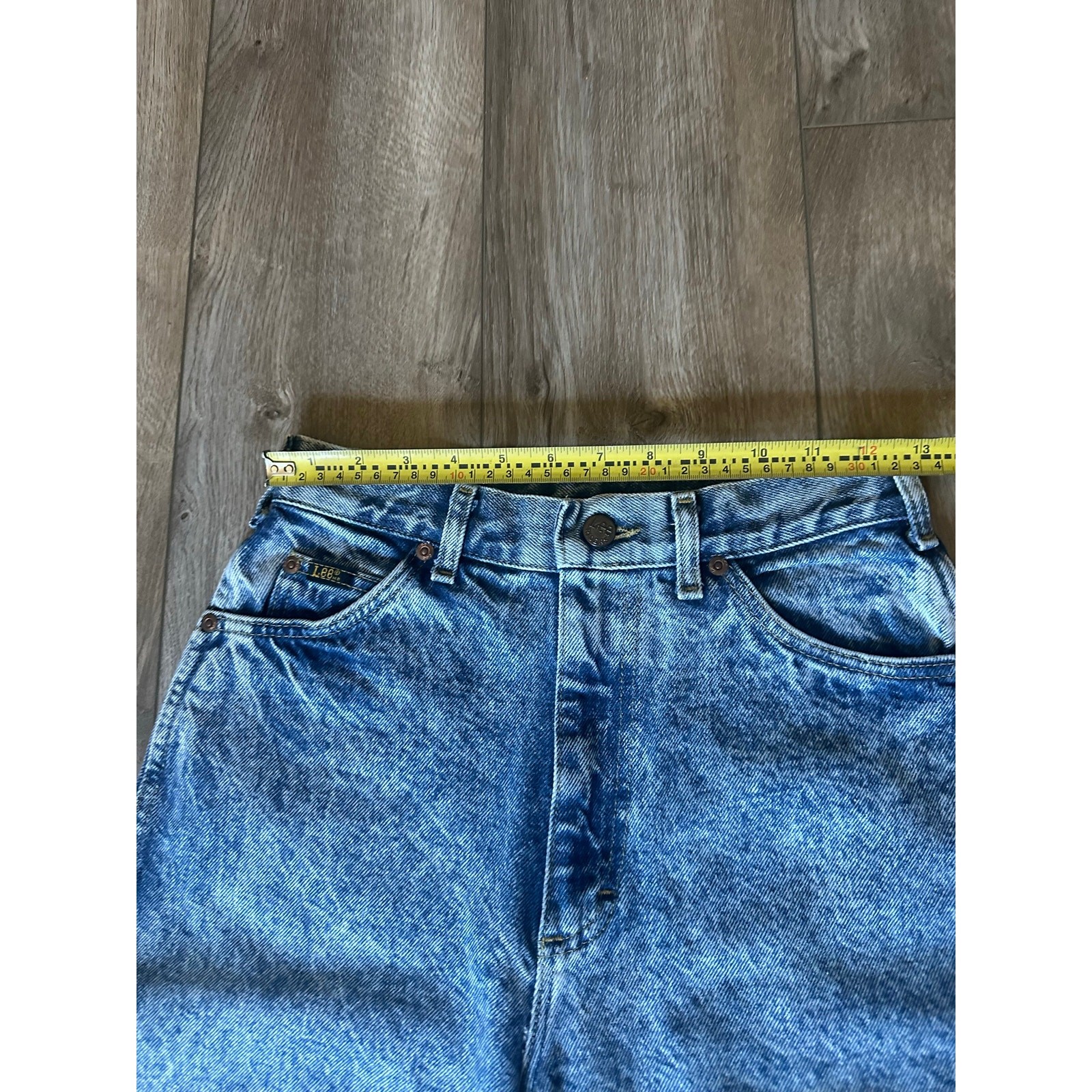 Light blue high-rise Lee mom jeans size 8 with faded front thighs, five pockets, and visible yellow measuring tape.