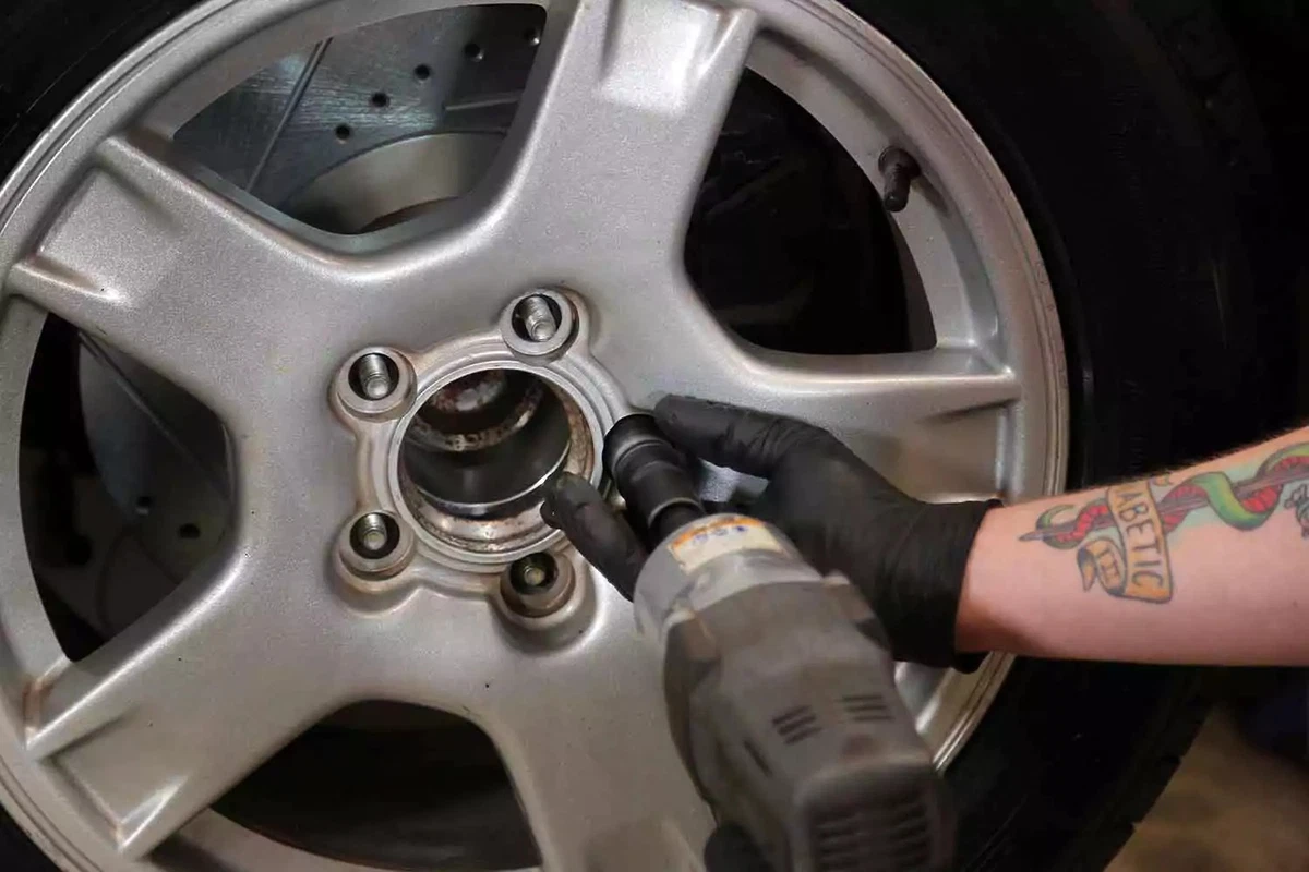 A mechanic removing a lug nut with an impact gun.