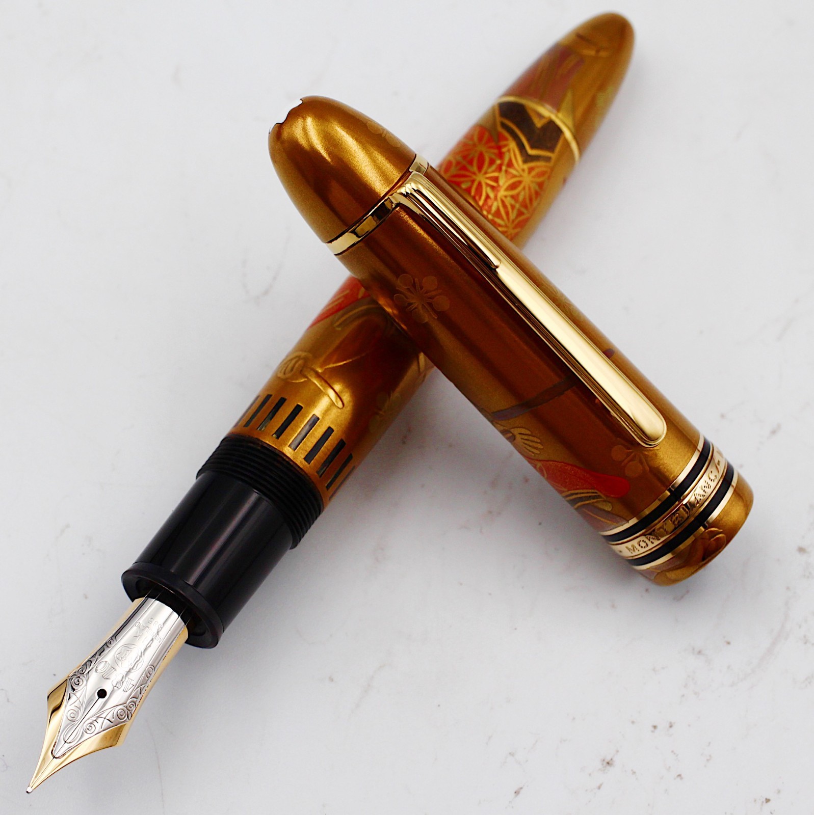 Gold Montblanc Meisterstuck 149 Makie Kabuki actor fountain pen with black nib and gold floral design on body, on white paper.
