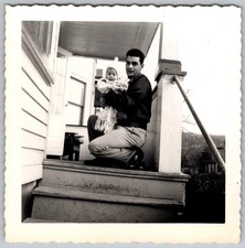 Vtg B&W Snapshot Man Kneeling On Porch Holding Baby in White Winter Cap 1956