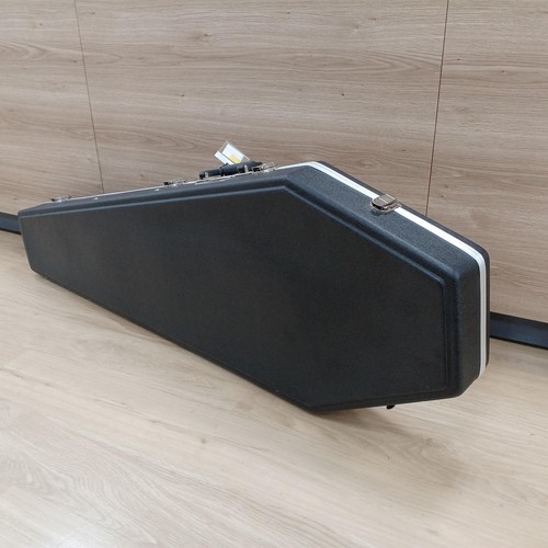 Black Squier Affinity P bass guitar case with silver edge, resting on light wood floor, one humbucker pickup visible.