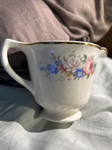 White ceramic mug with gold rim, blue and pink floral print, and “Made in U.S.A.” text on the side.