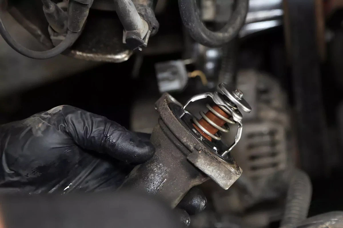 Mechanic holding the water neck with the old thermostat still in place.