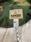 1980s vintage camouflage Ranger shirt with green and brown forest pattern, white “Ranger” label, and USA flag on collar.