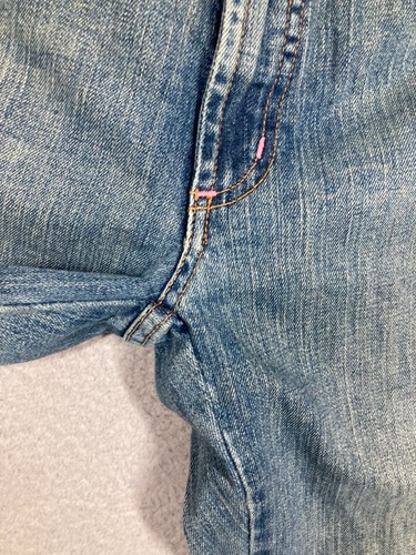 Light blue Karen Kane Lifestyle jeans with pink stitching and double button closure, rolled on a beige surface.