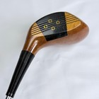 Vintage golf club head with black and gold accents, wooden shaft, silver screws, and black rubber grip.
