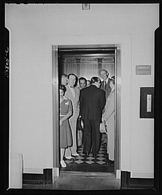 Photo:elevator crowd 1930s men women office building black white floor