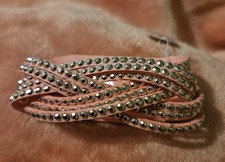 Girls pink braided bracelet or wrap with numerous small metallic studs.