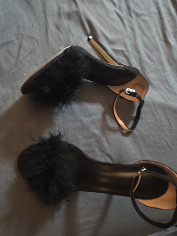 Black feather-trim stiletto sandals feature a delicate ankle strap and fluffy...