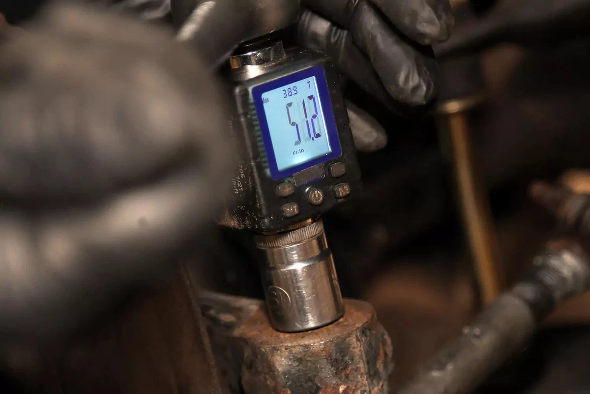 A mechanic uses a torque gauge to tighten the tie rod end to factory specifications.