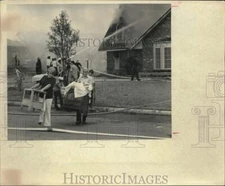 1972 Press Photo Gentleman & lady help carry items from burning home - saa64482