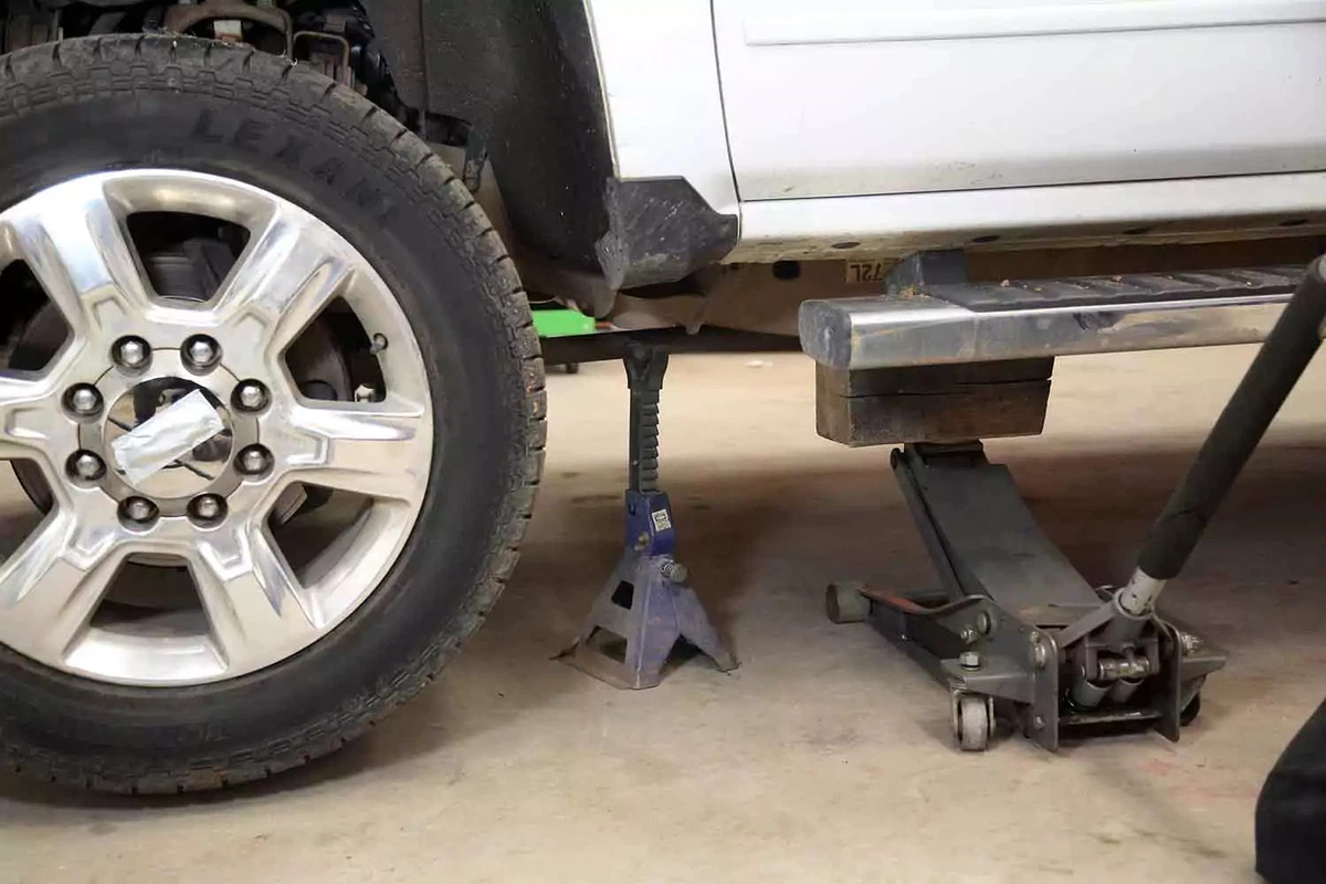 A truck raised with a jack stand, floor jack, and wood blocks.