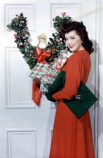 Ann Rutherford standing with Christmas presents next to a door OLD PHOTO