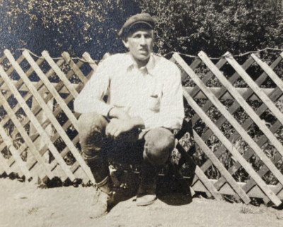 1910s Man Kneeling Down Against Wood Fence Fat Lip Newsboy Cap Real Photo P14z41