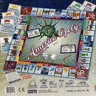 America-Opoly board game box with Statue of Liberty, red map, blue text, and colorful game pieces.
