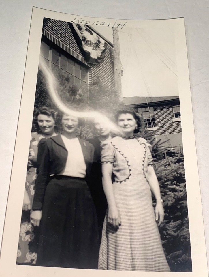 A 1944 WWII-era snapshot of patriotic women with a strange 'spirit line' artifact — history and the uncanny in a single frame.