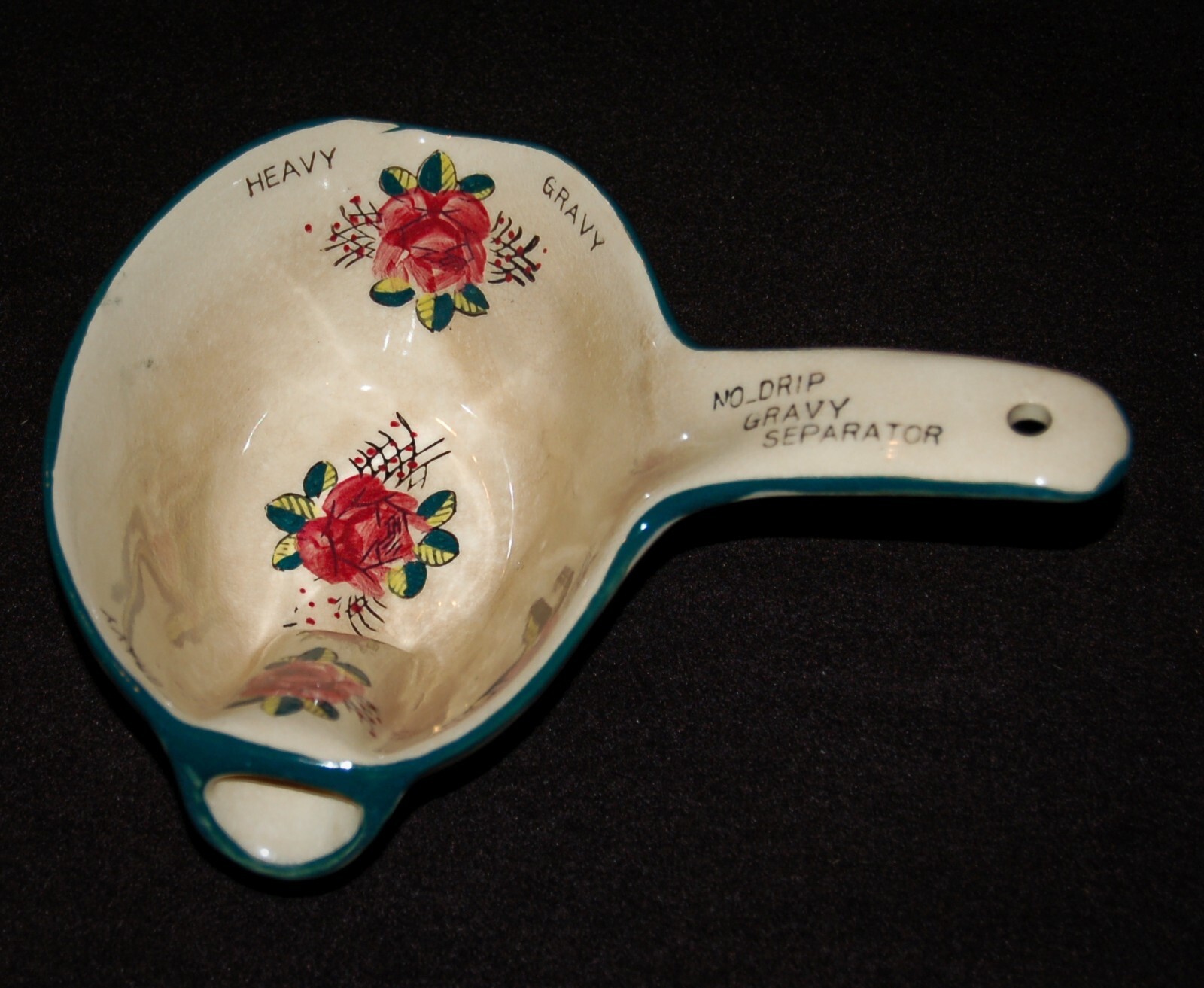 White ceramic gravy separator with red and green floral pattern, teal handle, and text “NO-DRIP GRAVY SEPARATOR” made in USA.