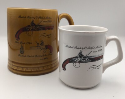 Feuerstein Duell Pistolen Design auf einem Stein Keramikkrug und einem weißen Becher