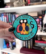 Snacky Snacks Cat Sticker – Black Cat Biting Skull Vinyl Decal for Laptop