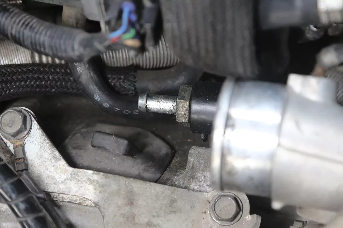 A closeup view of a vehicle's PCV valve after the vacuum line has been disconnected.