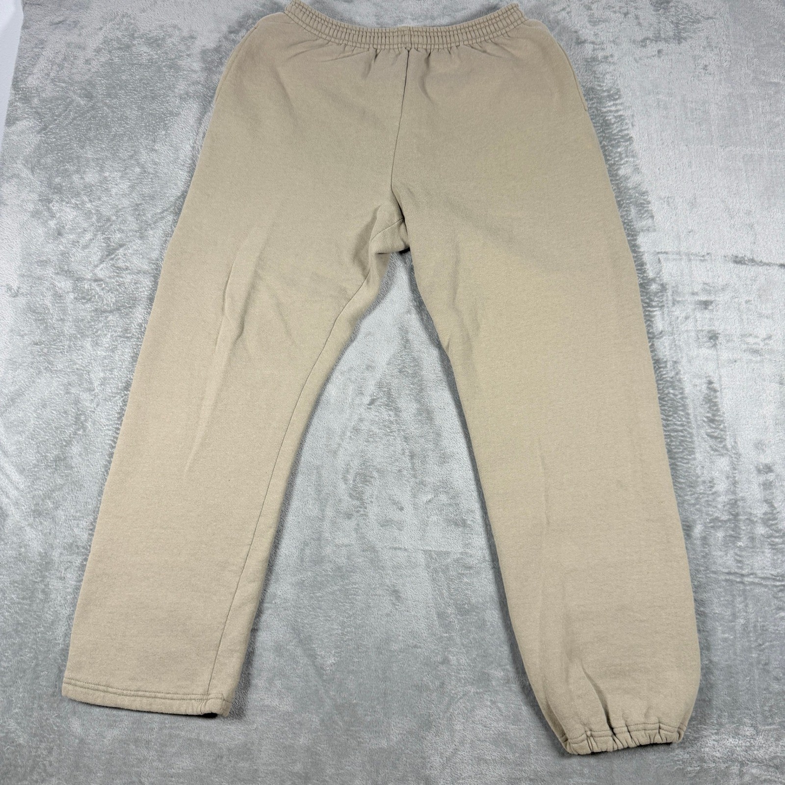 Tan khaki Russell Athletic Champs men’s XL sweatpants with elastic cuffs, laid flat on a textured light gray surface.