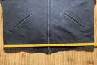 Black Carhartt J01 BLK Detroit jacket with two front zipper pockets and yellow measuring tape across the back.