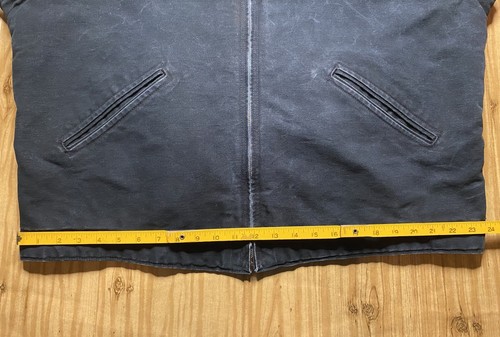 Black Carhartt J01 BLK Detroit jacket with two front zipper pockets and yellow measuring tape across the back.