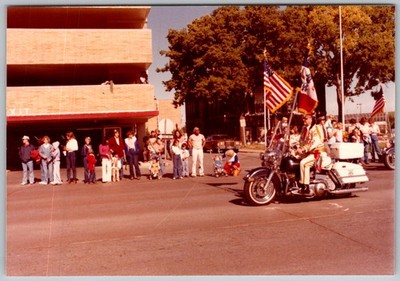 Vtg Color Snapshot Man On Motorcycle With Flags Leading Parade In Street 1979